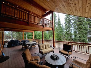 Une terrasse extérieure couverte avec un plancher en bois, une table à manger avec des chaises, un canapé et une table ronde décorée de pierres.
