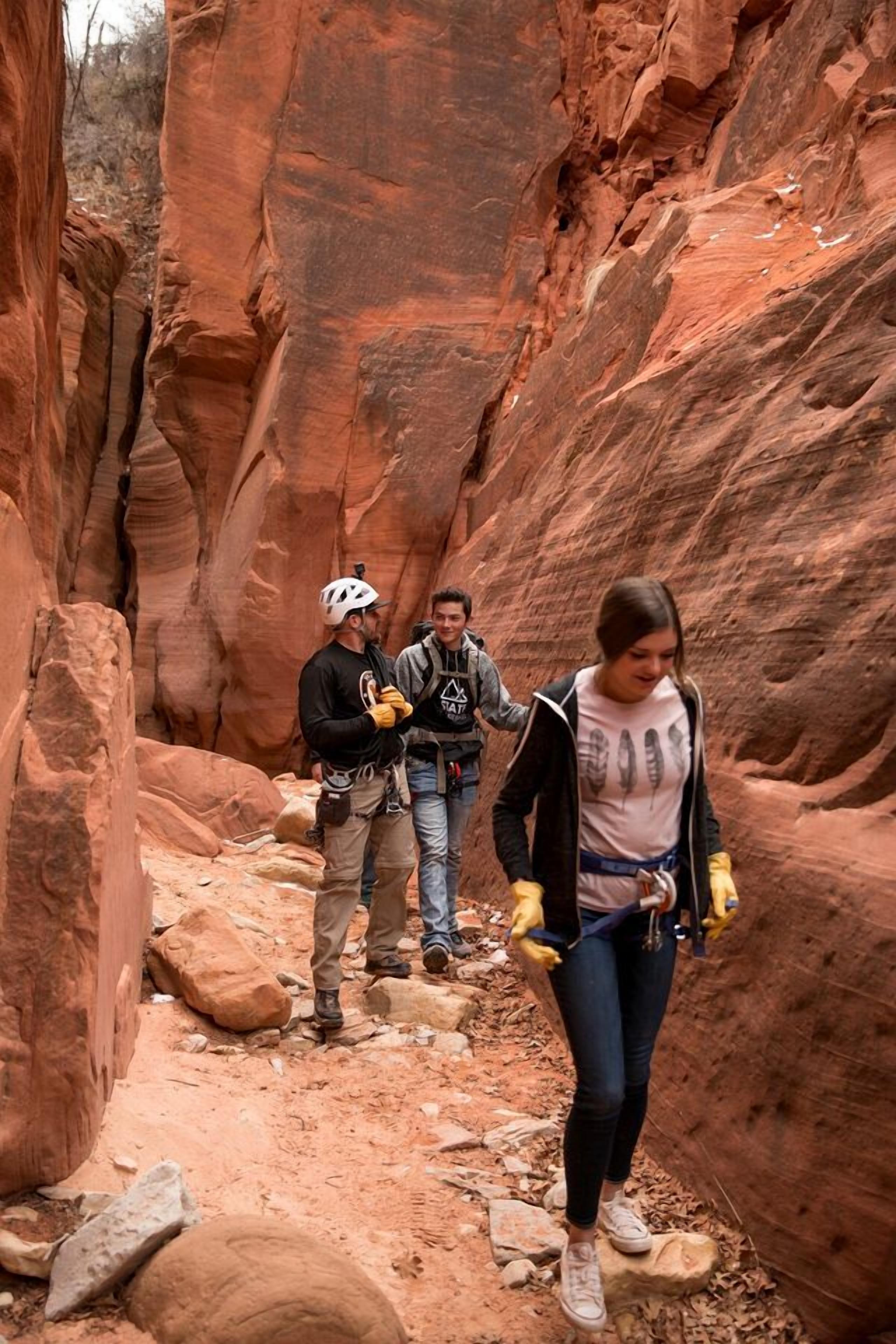 Un canyon étroit aux parois rocheuses, où un groupe de personnes fait de la randonnée.