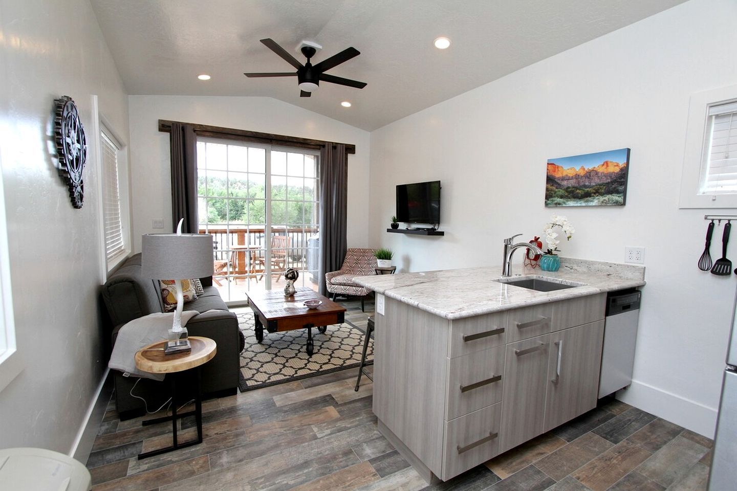 A modern kitchen with a large island, a dining area with a sofa and table, and a balcony with a view.