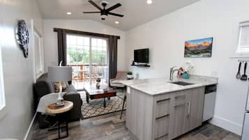 A modern kitchen with a large island, a dining area with a sofa and table, and a balcony with a view.