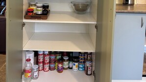 A kitchen pantry with shelves stocked with various food items, including jars, bottles, and kitchenware.