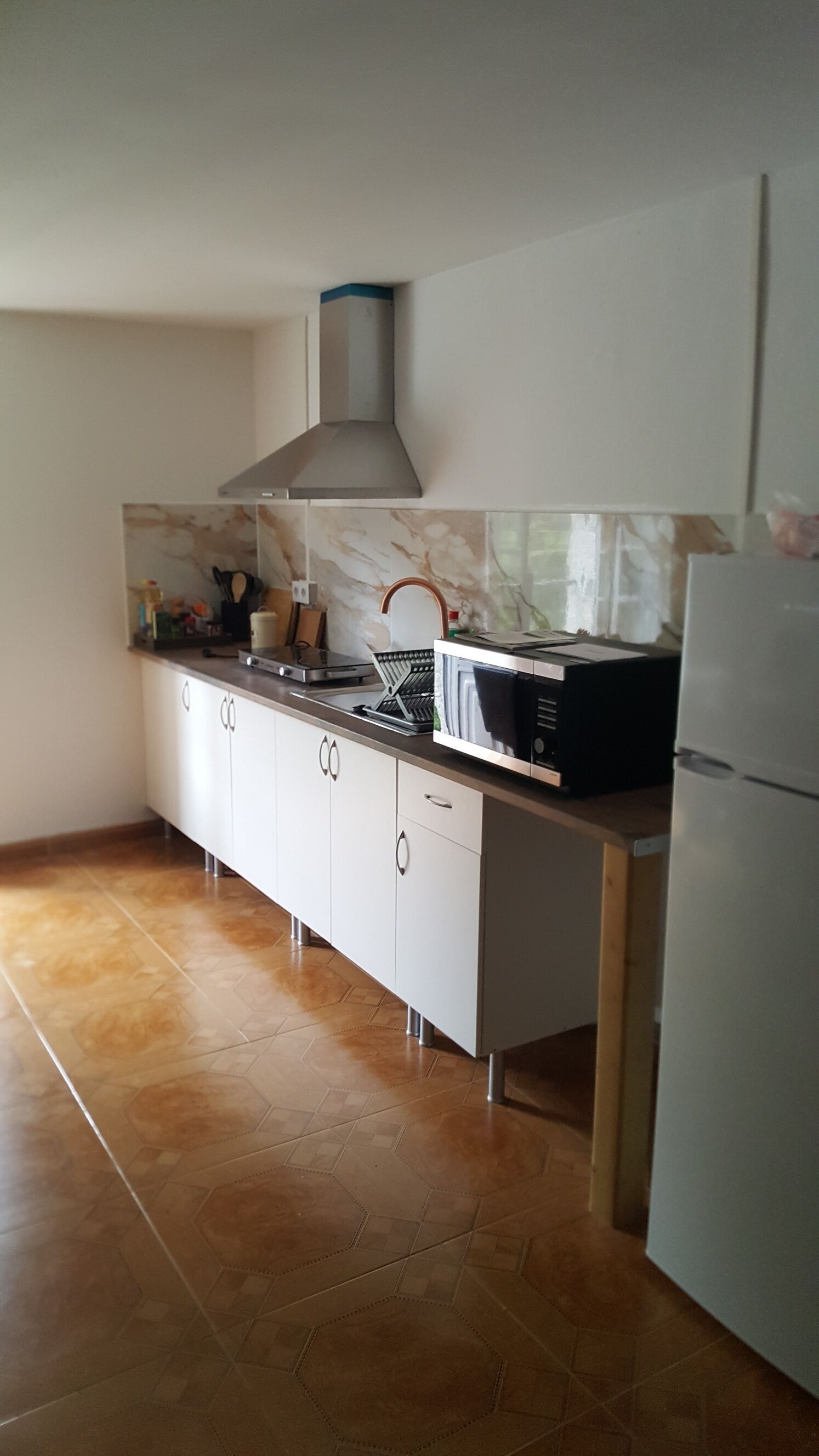 Een keuken met een magnetron, fornuis en koelkast.