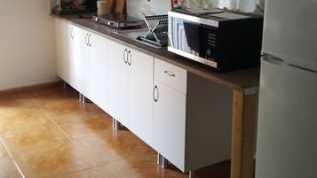 Een keuken met een magnetron, fornuis en koelkast.