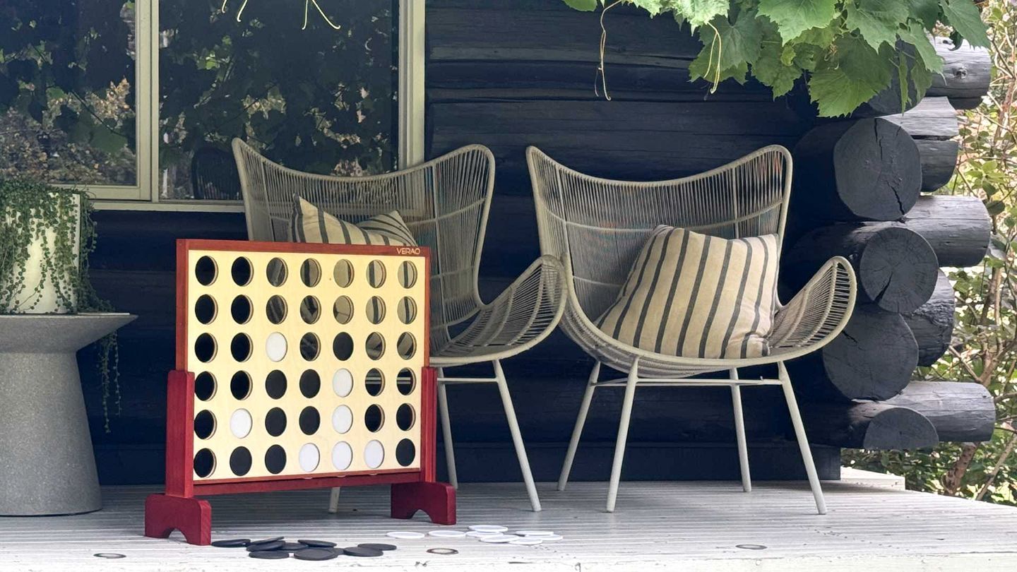 A wooden deck with two wicker chairs and a wooden puzzle table.