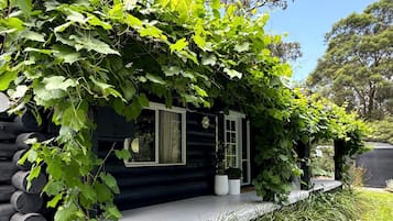 A log cabin with a covered porch, large windows, and a potted plant on the deck.