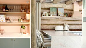 A kitchen with a marble countertop, a toaster, and a coffee maker. There are shelves with wine bottles and glasses.