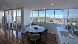 Ein modernes Zimmer mit einem großen Fenster, einem runden Tisch und Blick auf eine Skyline.