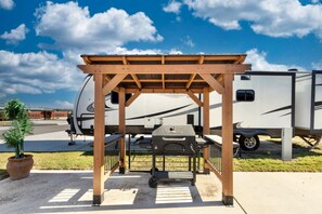 A covered RV parking area with a grill and a potted plant. - Rustic-Modern Tiny Home Retreat with Resort Amenities Near Fredericksburg, TX (Fredericksburg)