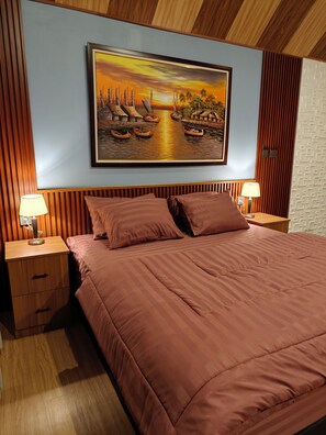 A bedroom with a large bed, two bedside tables, a nightstand, a wall-mounted painting, and a wooden ceiling.