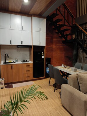 A modern kitchen with white cabinets, a black refrigerator, and a dining area with a table and chairs.