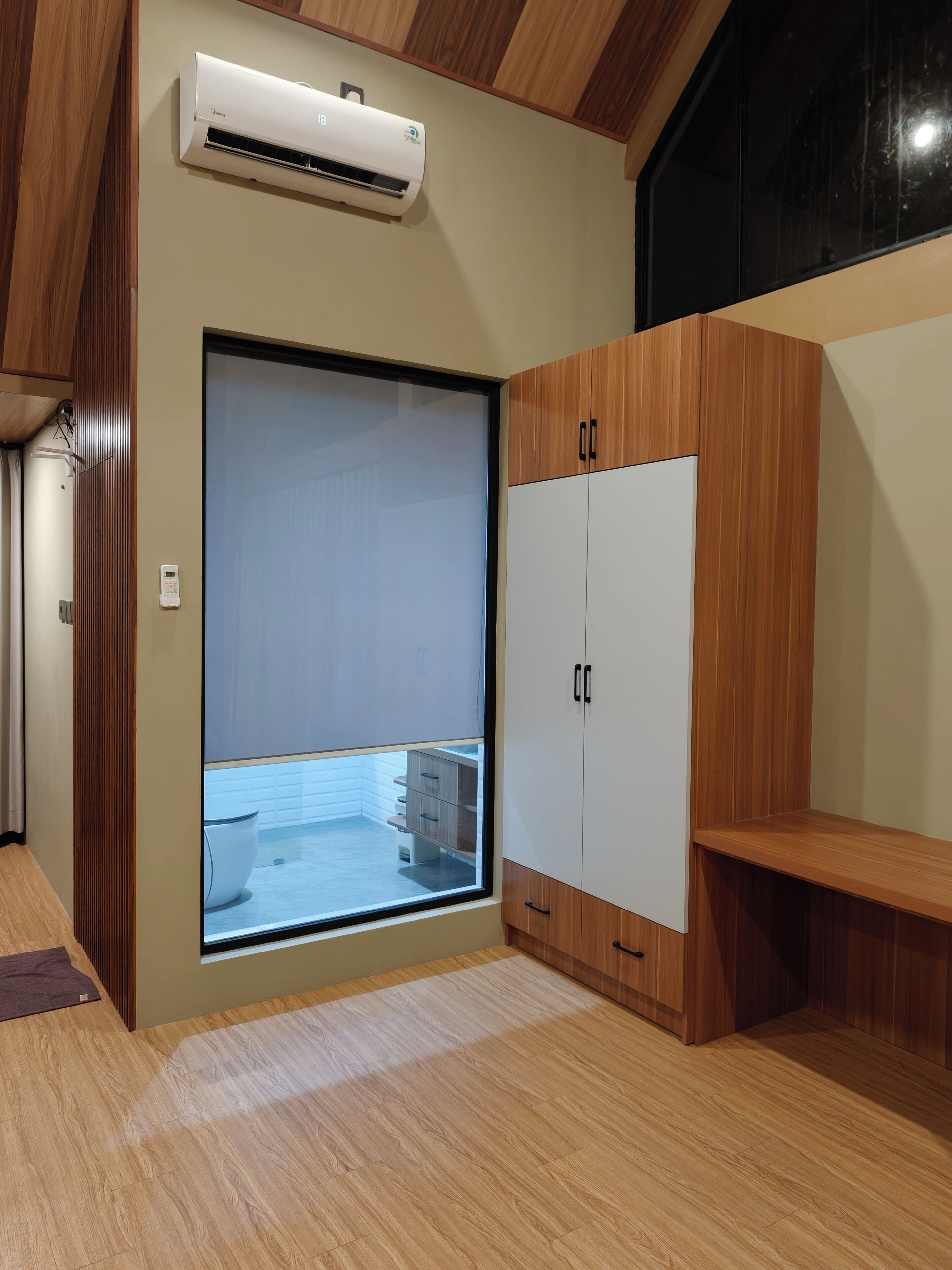 A room with a sliding door leading to a balcony, a built-in wardrobe, and an air conditioning unit.