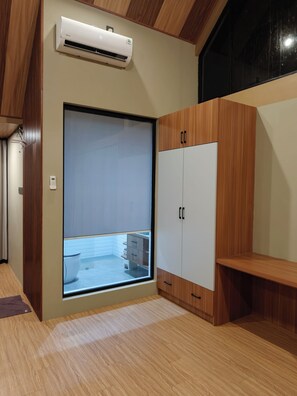 A room with a sliding door leading to a balcony, a built-in wardrobe, and an air conditioning unit.
