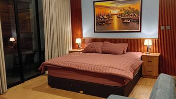 A modern bedroom with a large bed, a painting of a sunset scene, and a sliding glass door leading to an outdoor area.