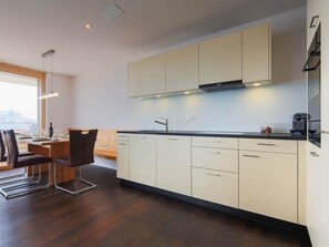 Eine moderne Küche mit weißen Schränken, einer schwarzen Arbeitsplatte und einem Essbereich mit einem Holztisch und Stühlen.