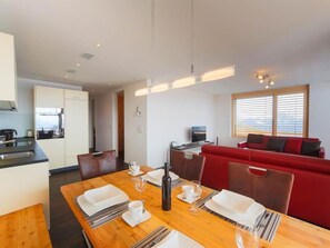 Una cocina moderna con comedor, un sofá rojo y un ventanal grande.