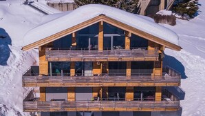 Una cabaña de madera de varios pisos con balcones, ubicada en un paisaje nevado.