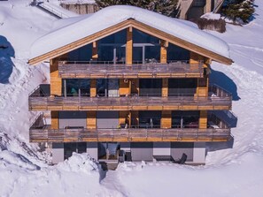 Eine mehrstöckige Holzhütte mit Balkonen in verschneiter Landschaft.