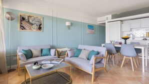 A modern living room with a sofa set, a coffee table, and a dining area with chairs and a table. - Mondello Bay - Addaura Apartments (Palermo)
