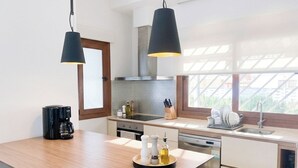 Et moderne køkken med en træø, rustfrie stål-hvidevarer og hængende lamper.