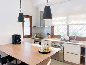 Eine moderne Küche mit einer Holztischinsel, Edelstahlgeräten und Pendelleuchten.