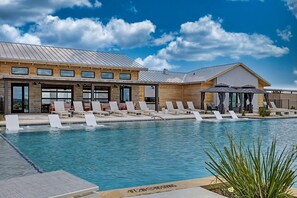 A pool area with lounge chairs and a building with large windows. - Serene Tiny Home Retreat with Resort Amenities Near Fredericksburg, TX (Fredericksburg)