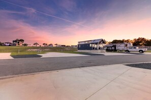 A modern building with a covered outdoor area, a parking lot, and a white pickup truck. - Serene Tiny Home Retreat with Resort Amenities Near Fredericksburg, TX (Fredericksburg)