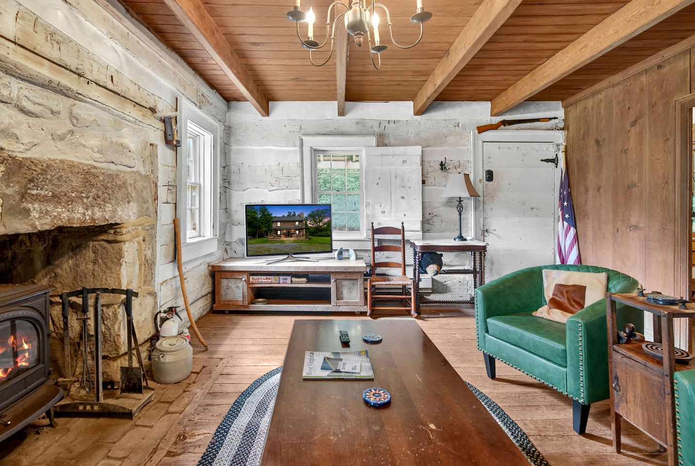 A rustic living room with a fireplace, television, wooden furniture, and a green armchair.