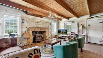 Un interior rústico con chimenea de piedra, vigas de madera, televisor y una zona de estar acogedora.
