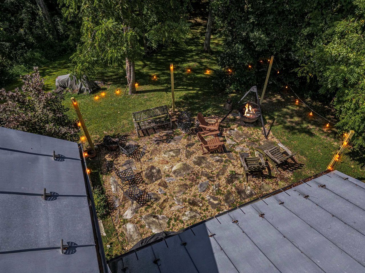 Ein Garten mit Feuerstelle, Sitzgelegenheiten im Freien und einem Zelt.