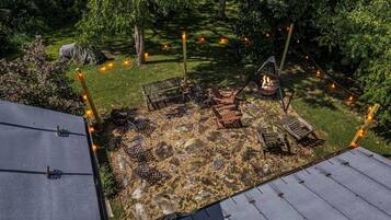 Ein Garten mit Feuerstelle, Sitzgelegenheiten im Freien und einem Zelt.