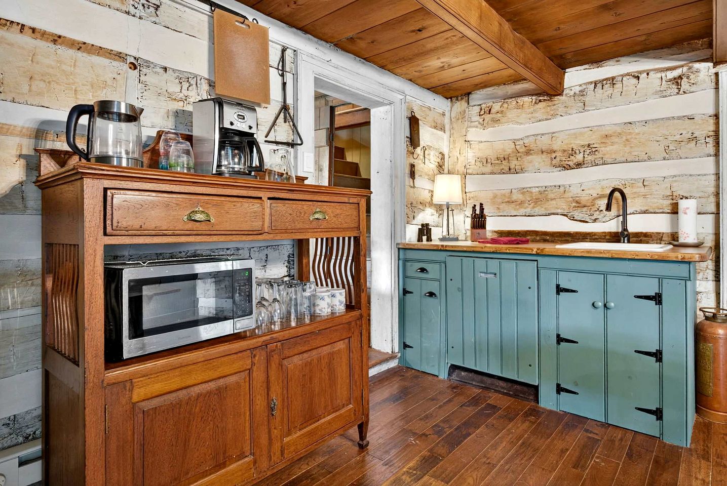 A rustic kitchen with wooden cabinetry, a built-in microwave, and a coffee maker.
