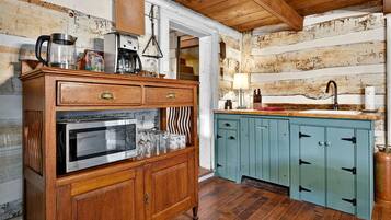 A rustic kitchen with wooden cabinetry, a built-in microwave, and a coffee maker.
