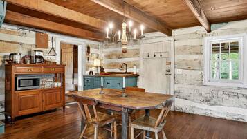 A rustic kitchen with wooden cabinets, a dining table, and a chandelier.