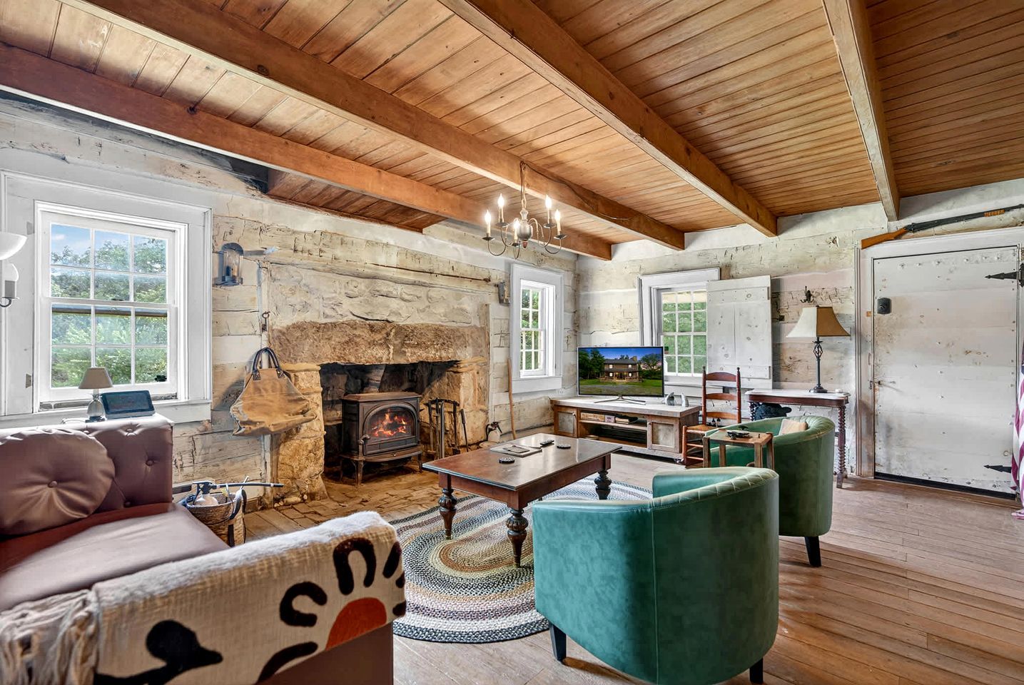 A rustic interior with a stone fireplace, wooden beams, a television, and a cozy seating area.