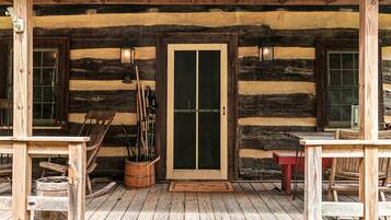 A rustic wooden cabin with a porch, a door with glass panels, and a wooden bench.