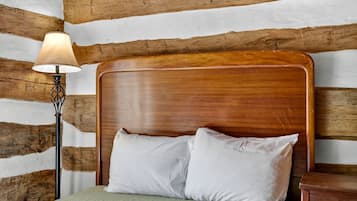 A wooden headboard bed with white pillows, a bedside lamp, and a green textured bedspread.