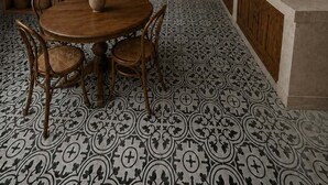 Un espace repas comprenant une table ronde en bois et des chaises, un escalier, ainsi qu’un coin cuisine avec un évier et des placards.