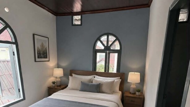 Une chambre à coucher avec un lit, deux tables de chevet avec des lampes, une fenêtre et un sol à motifs.
