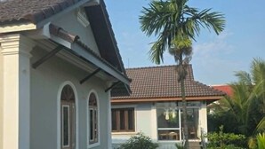 Une maison à deux étages, avec un toit recouvert de tuiles, un balcon et un palmier dans la cour.