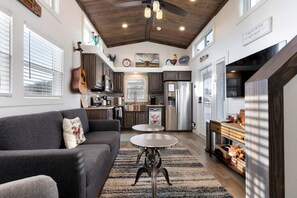 A compact living space with a kitchenette, a sofa, a dining table, and a ceiling fan. - Welcoming Tiny Home Getaway with Resort Amenities Near Fredericksburg, TX (Fredericksburg)
