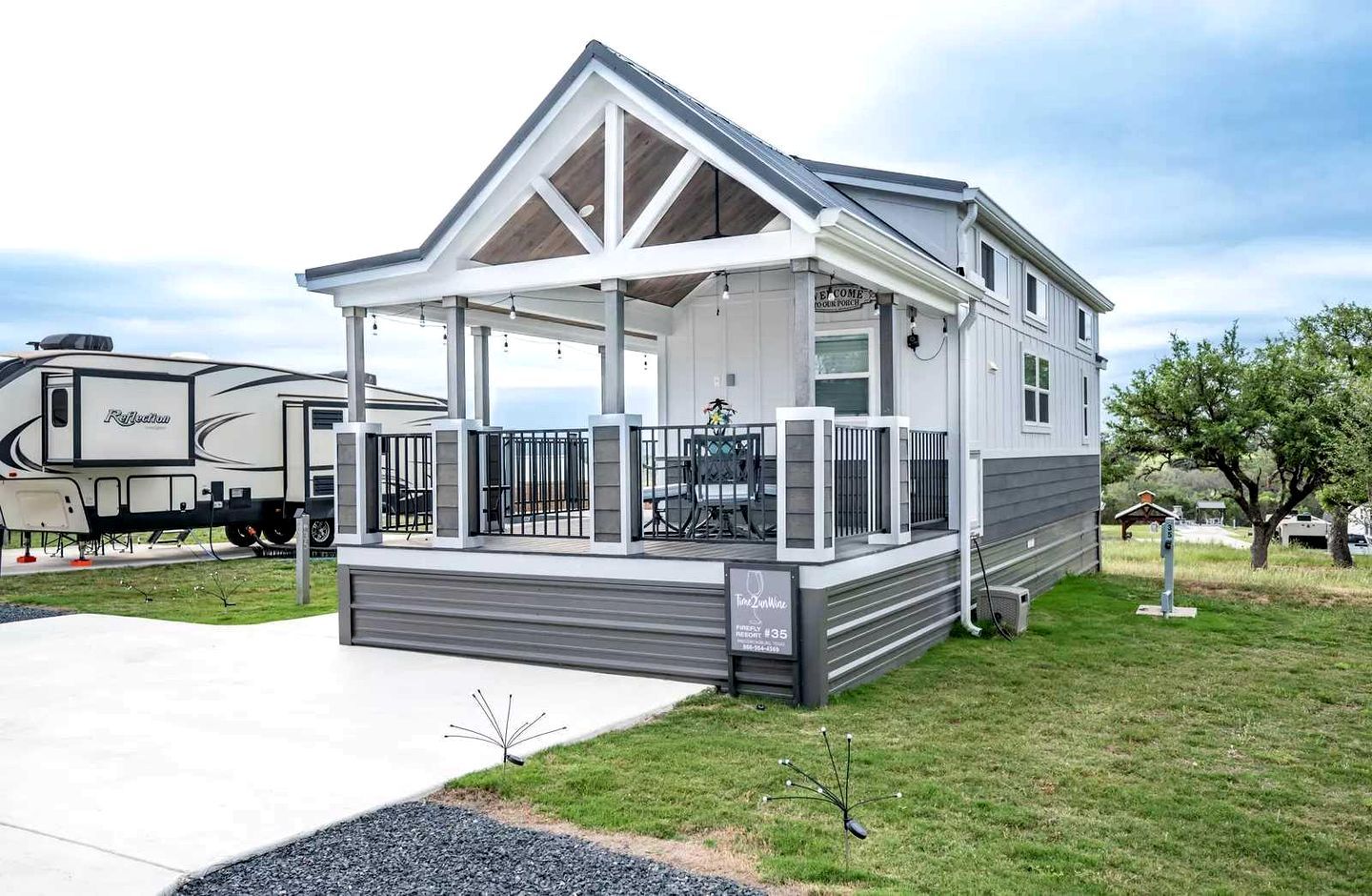 A mobile home with a covered porch, a fenced outdoor area, and a driveway.