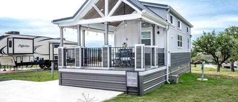 A mobile home with a covered porch, a fenced outdoor area, and a driveway.
