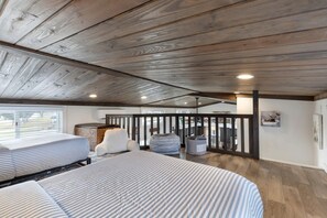 A bedroom with a sloped ceiling, a bed with striped bedding, a window, and a view of the outdoors. - Welcoming Tiny Home Getaway with Resort Amenities Near Fredericksburg, TX (Fredericksburg)