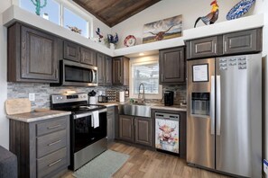 Une cuisine moderne avec des meubles en bois foncé, des appareils électroménagers en acier inoxydable et un style inspiré des fermes.