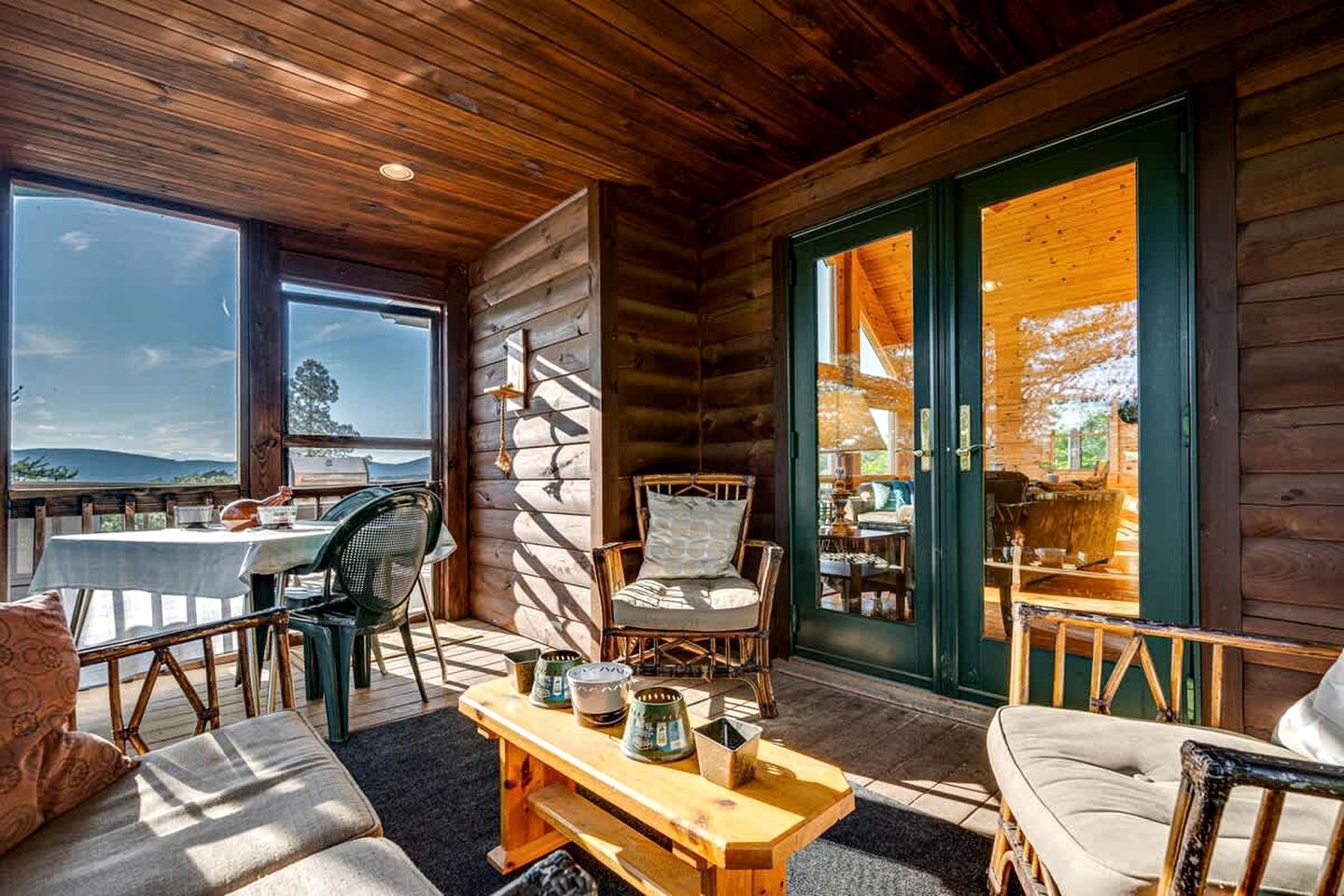 Interior acogedor de una cabaña con comedor, asientos y vistas por la puerta.
