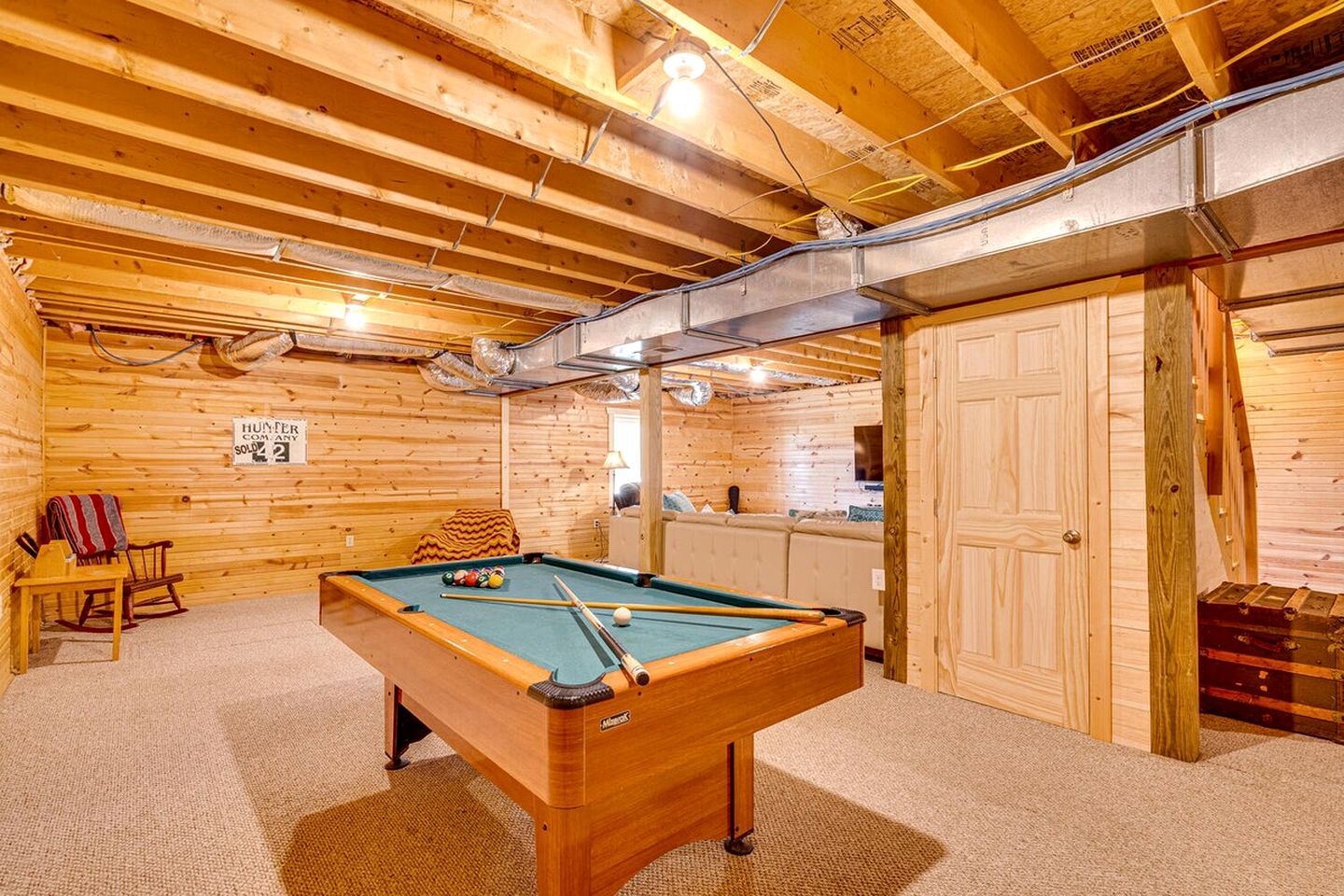 Un intérieur en bois avec une table de billard, un canapé et un panneau indiquant une vente.
