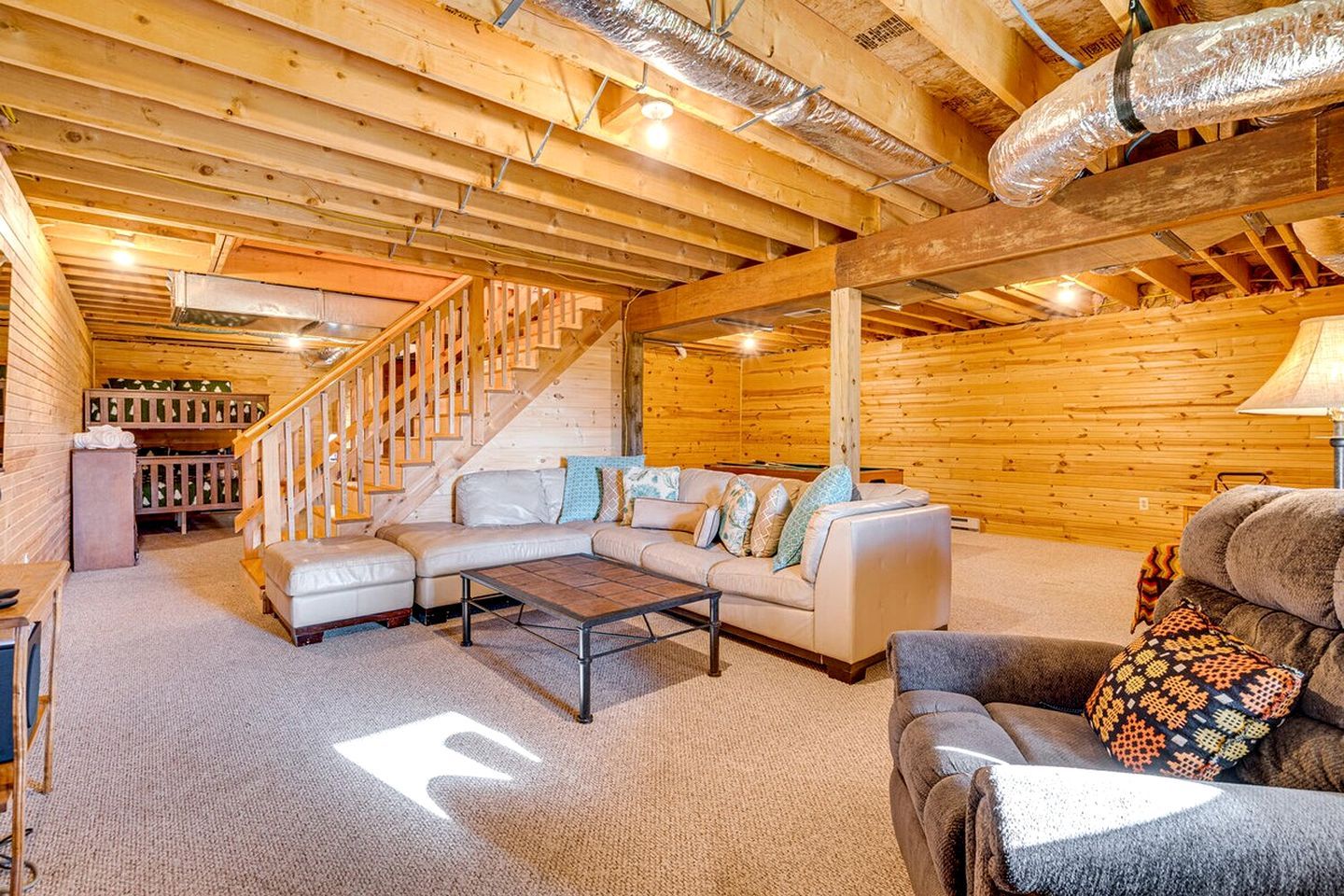 A cozy interior with a wooden staircase, a sectional sofa, and a patterned throw pillow.