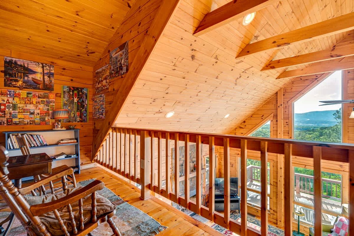 Interior de madera con techo inclinado, estanterías, una zona de estar y un balcón con vistas.