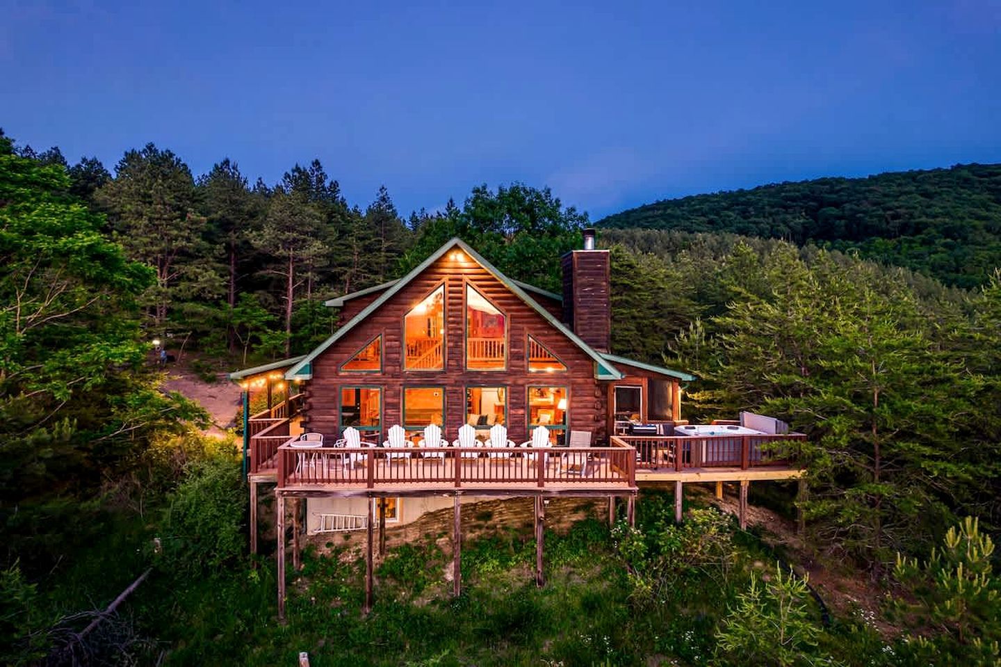 A log cabin with a deck, surrounded by forest.