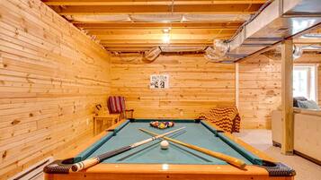 A pool table with cues and balls, a sign indicating a sold-out event, and wooden walls.